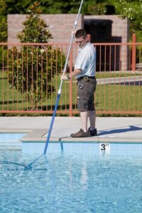 Pool technician vacuuming a swimming pool.